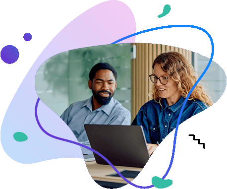 Dwoje współpracowników rozmawiających z&nbsp;uśmiechem przed ekranem laptopa w&nbsp;nowoczesnym biurze.