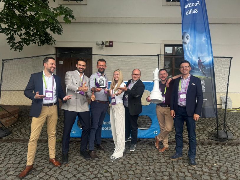 Siedmioosobowy zespół uśmiechniętych profesjonalistów pozuje na&nbsp;zewnątrz z&nbsp;nagrodą Unchain Innovation Excellence Award.